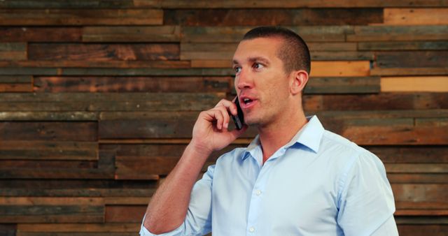 Young Professional Talking on Phone in Front of Wooden Wall - Download Free Stock Images Pikwizard.com