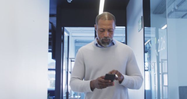 Businessman Checking Smartphone in Modern Office Corridor - Download Free Stock Images Pikwizard.com