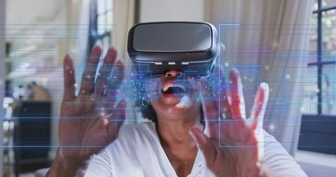 Senior woman experiencing virtual reality headset and touching holographic interface