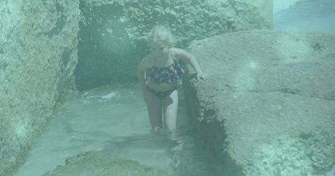 Child exploring rocky shore in tropical beach area