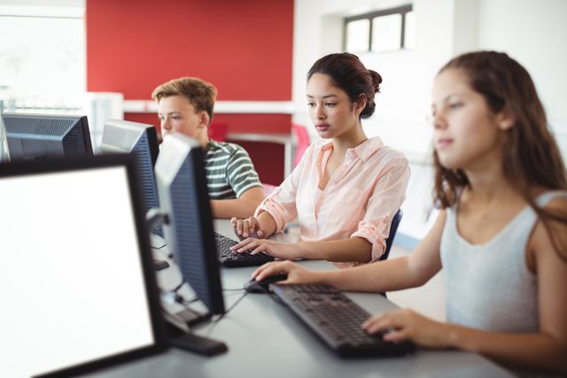 Students are using computers in a classroom, focusing on their tasks. This image can be used for educational websites, school brochures, technology in education articles, and academic presentations.