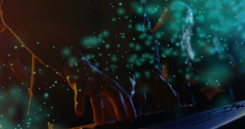 Hands typing on backlit keyboard with teal bokeh particle overlay and moody rim light