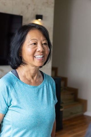 Smiling Senior Asian Woman at Home in Modern Living Room Setting