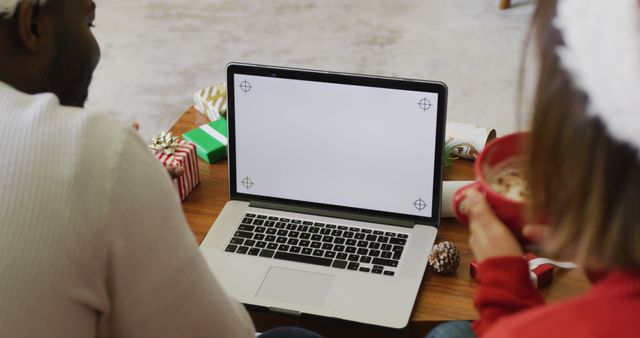 Image of happy diverse couple making christmas laptop image call at home, copy space on screen. Christmas, celebration, communication, happiness and inclusivity concept.