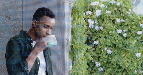 Man sipping coffee on terrace with binary code overlay, tech-nature lifestyle remote work concept
