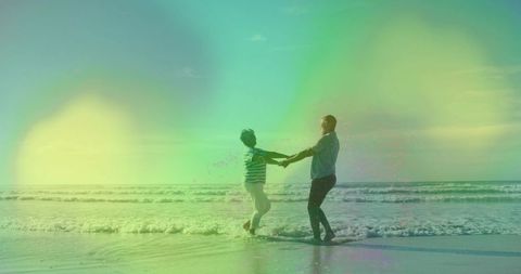 Couple Holding Hands Spinning in Surf at Sunset with Lens Flare and Wet Sand Reflections