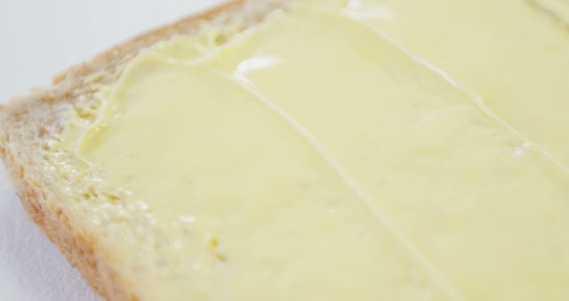 A close-up view of a slice of bread with a spread of butter, with copy space. The image captures the texture of the melted butter on the bread's surface, suggesting a simple breakfast or snack option.