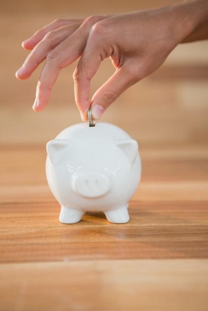 Hand inserting coin in piggy bank - Download Free Stock Photos Pikwizard.com