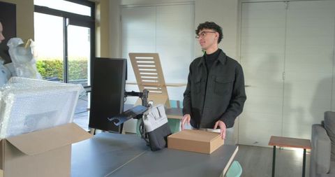 Young housemates unpacking office equipment during move, creating modern home workspace