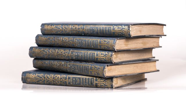 Collection of old vintage books stacked on top of each other, showcasing ornate covers and yellowed pages. Ideal for use in themes related to historical literature, libraries, academic environments, or antique collections. The image conveys a sense of tradition, knowledge, and timelessness.