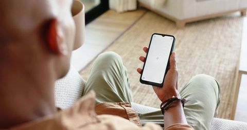 Relaxing on sofa holding smartphone and steaming mug morning routine minimal cozy