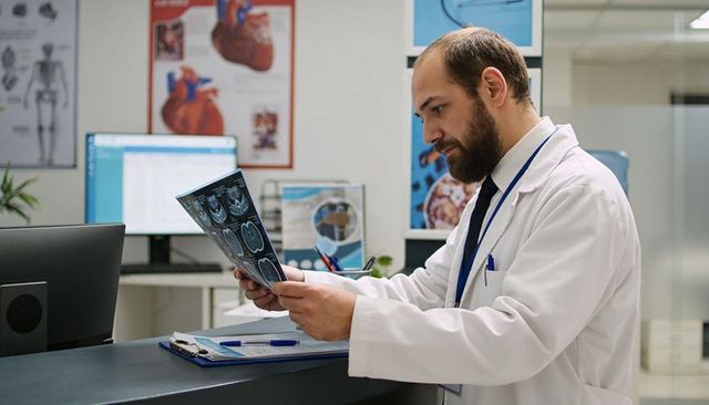 Physician reviewing brain mri scans at clinic reception for diagnostic radiology consult
