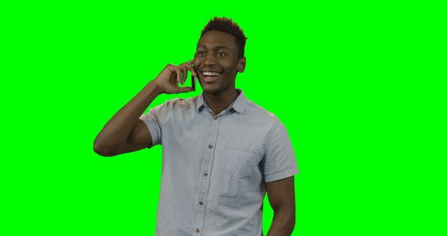 Smiling man talking on mobile phone against green screen