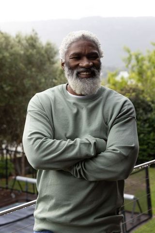 Senior african american man smiling on backyard deck in sage sweater