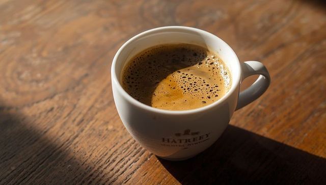 Warm coffee in sunlit ceramic cup on rustic wooden table