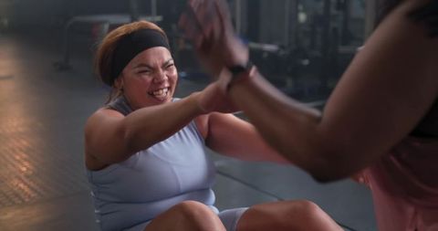 Multiracial women doing partner core workout showing strength and team support