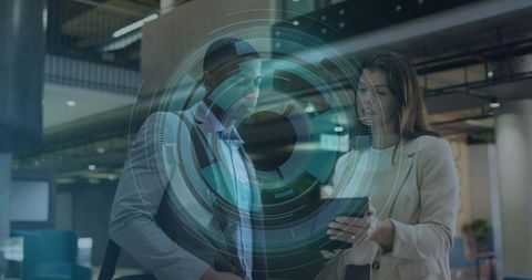 Business professionals discussing tablet with augmented reality HUD in modern glass atrium