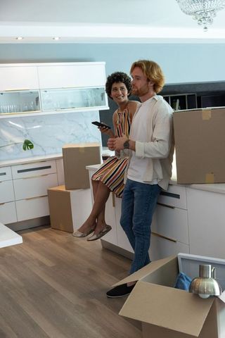 Diverse couple unboxing in modern kitchen with smartphone