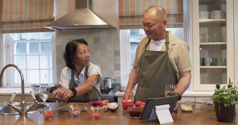 Senior couple cooking together with tablet in kitchen