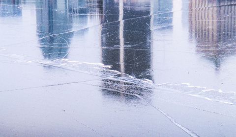 City skyline reflecting on cracked winter ice with textured urban surface