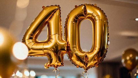 Gold foil 40 balloons celebrating milestone birthday anniversary with warm bokeh lights