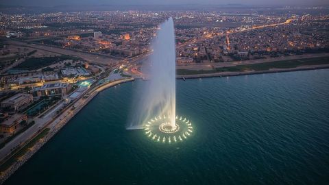 Illuminated waterfront fountain jetting into evening sky