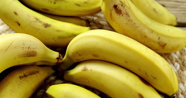 Ripe yellow bananas grouped together showing small brown spots. Can be used for healthy food advertisements, grocery store promotions, recipes, nutrition blogs, or informing about the benefits of organic living.