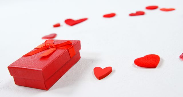 Red gift box and red hearts on white surface. Valentines day concept 4k