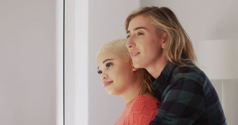 Happy Multiracial Couple Embracing Near Window at Home
