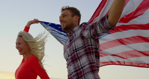 Joyful Couple Celebrating with American Flag on Sunset Beach