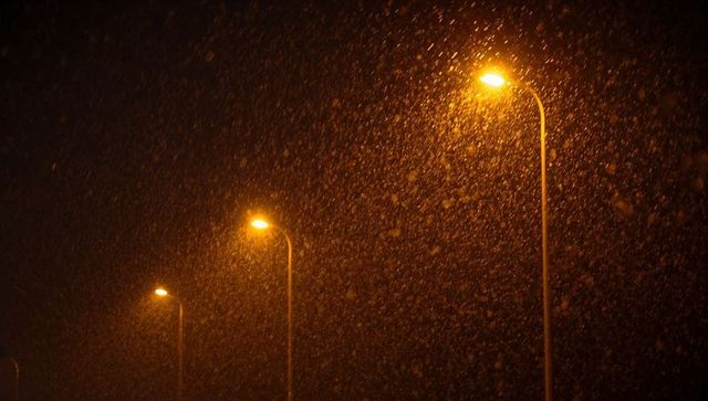 Warm streetlights glowing through heavy snowfall at night creating golden urban bokeh and mood