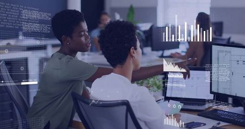 Two coworkers collaborating over data dashboards, analytics and UI design on dual monitors