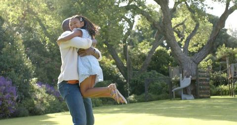 Father and daughter embracing joyfully in sunlit backyard