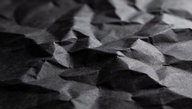 Black Crumpled Paper Texture Revealing Sharp Creases, High Contrast, Macro Closeup Detail