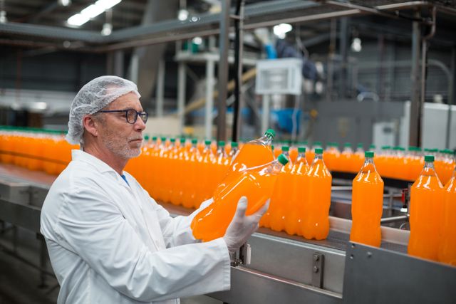 Factory engineer examining a bottle of juice in bottle factory