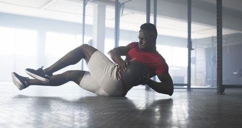 Athletic Man Engaging in Intense Gym Workout with Medicine Ball