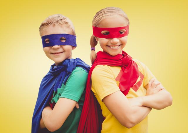 Two children wearing vibrant superhero costumes, including masks and capes, standing back-to-back and smiling confidently against a yellow background. Ideal for use in promotional materials related to teamwork, imagination, children’s events, playful activities, and creativity.