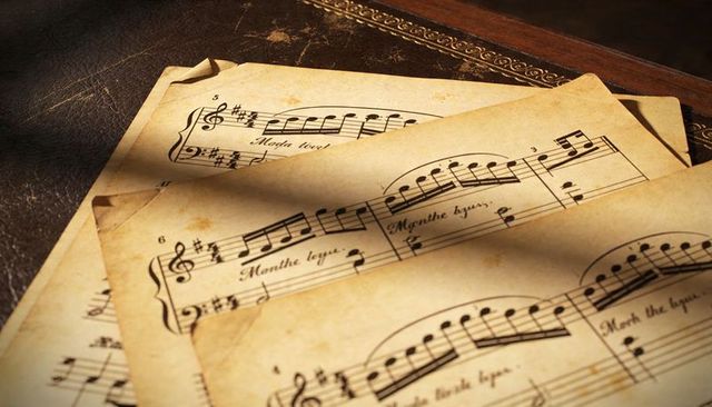 Aged vintage sheet music on leather with sepia tones and dramatic shadow play