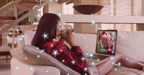 Woman Enjoying Virtual Christmas Call with Family Amid Falling Snow
