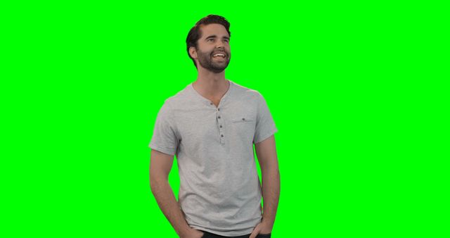 The image shows a man in a light grey t-shirt smiling and standing against a green screen background. This image can be used for advertising, promotional materials, or as a template for digital media requiring a green screen. Ideal for marketers looking to superimpose their branding or creative elements. Useful for web designers, content creators, and digital projects.