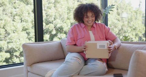 Cheerful woman receiving package at home in modern living room
