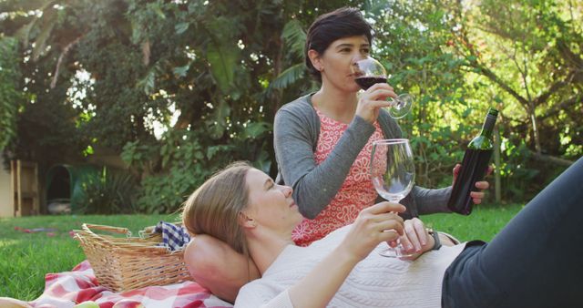 Caucasian lesbian couple drinking wine together in the garden during picnic - Download Free Stock Photos Pikwizard.com