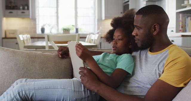 Father and daughter bonding on couch reading digital tablet - Download Free Stock Images Pikwizard.com