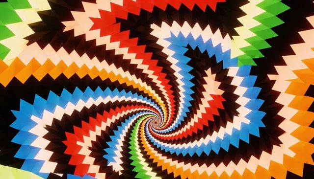 Rotating chevron spiral vortex with zigzag bands and vibrant kaleidoscope colors