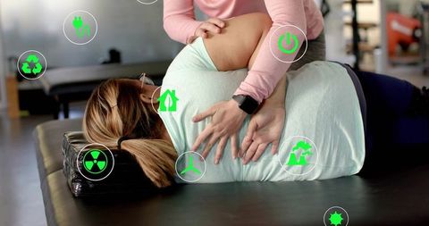 Clinician mobilizing patient shoulder during manual therapy with green augmented icons