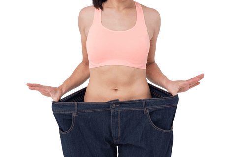 Happy woman displaying significant weight loss in loose jeans transparent