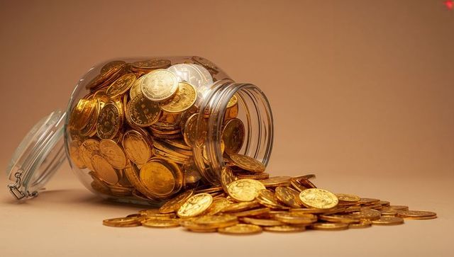 Spilling glass jar of gold coins representing wealth and cryptocurrency