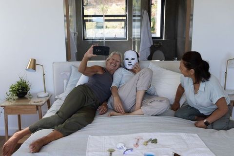 Three friends enjoying at-home skincare night taking selfie with led face mask and rollers
