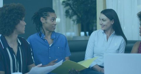 Young adults collaborating on project, holding yellow folder and laptop in casual meeting