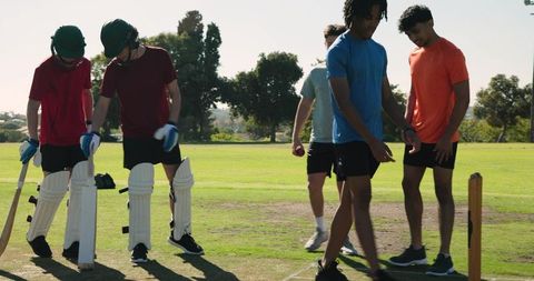 Youth cricket team preparing for match on sunny outdoor pitch